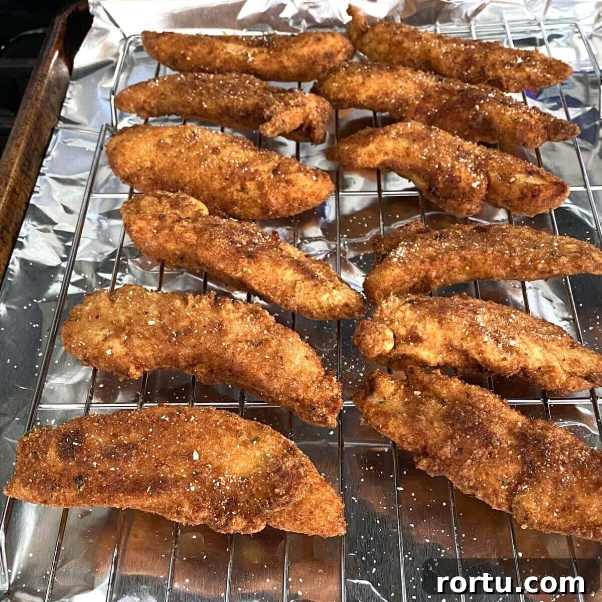 Crispy Buttermilk Fried Chicken Tenders Recipe 4 fried buttermilk chicken tenders on a baking rack.