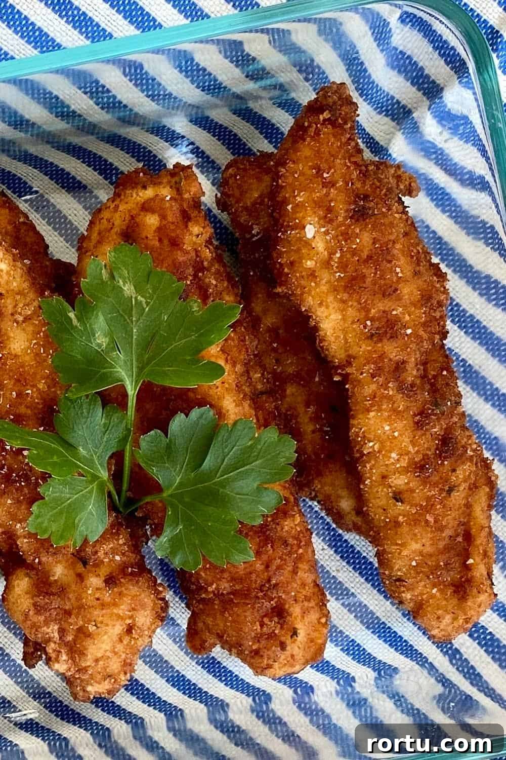Crispy Buttermilk Fried Chicken Tenders Recipe 5 buttermilk fried chicken tenders on striped mat.