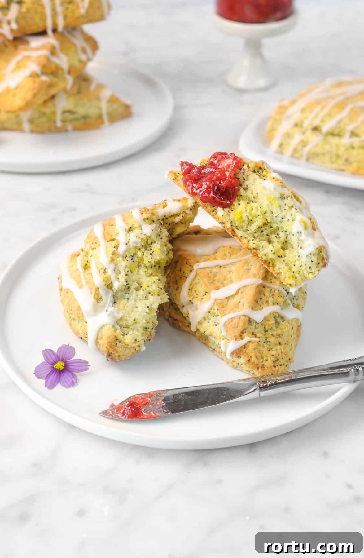 Giant Lemon Poppy Seed Scones — Soft, Zesty Breakfast Treat 9 scone broken open with jam spread on it with a purple flower