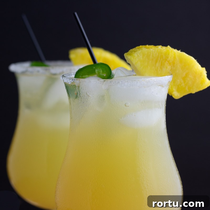 two glasses of sweet hot mama cocktail closeup with pineapple and jalapeño