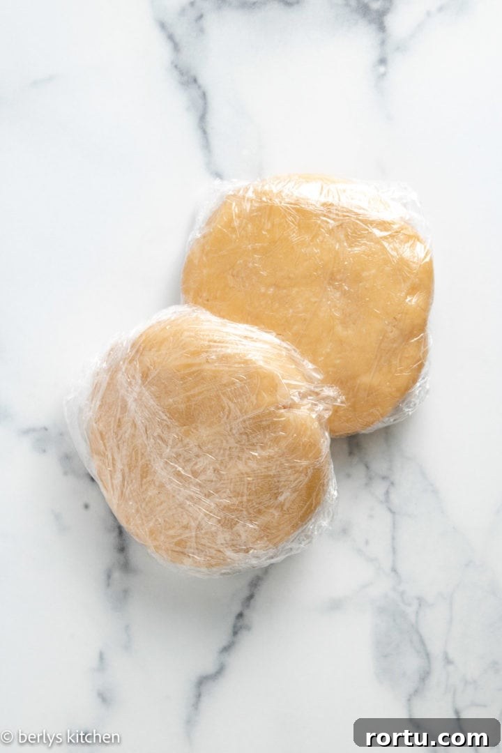 Two discs of pie crusts wrapped in plastic wrap.
