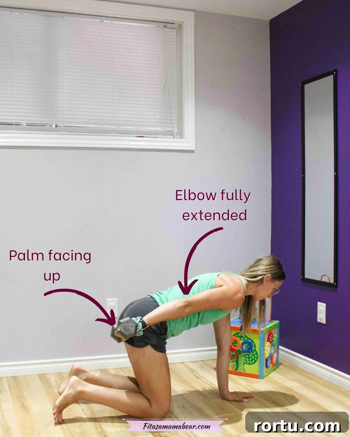 10 Targeted Exercises for Bat Wings + a 10-Minute Arm Routine 6 Woman in green shirt and black shorts in tabletop potion with a dumbbell in one arm extended back by her hip