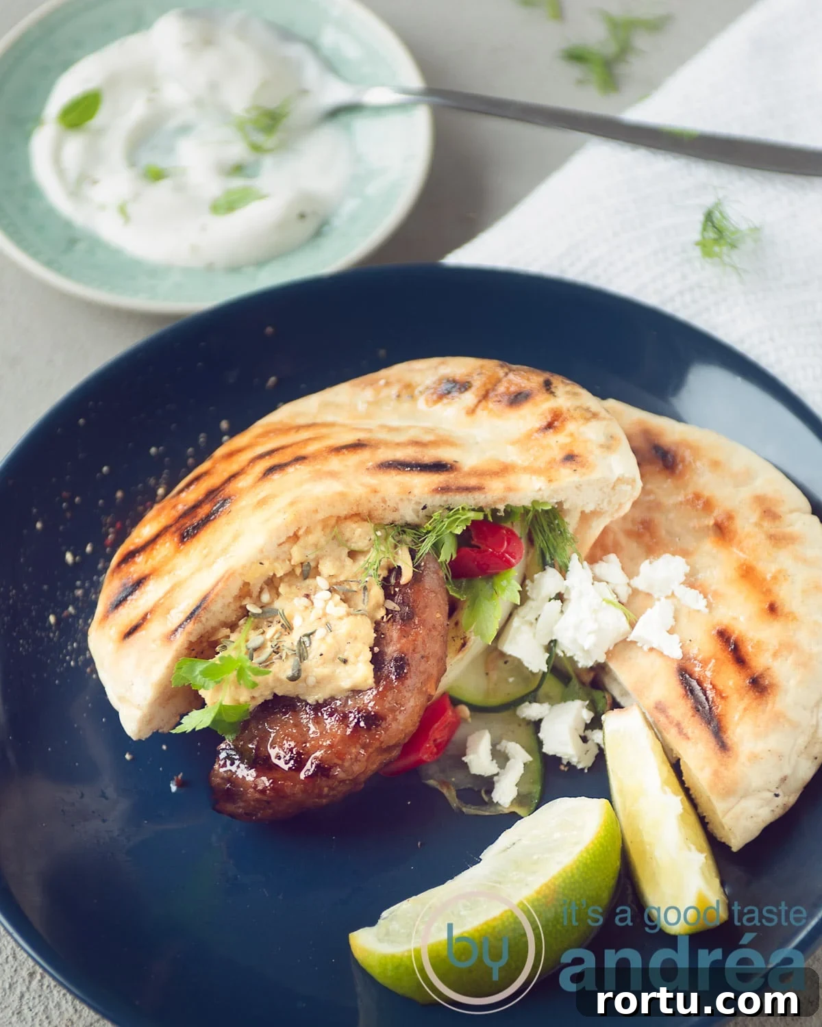 A blue plate with grilled vegetables, hamburger and feta cheese.