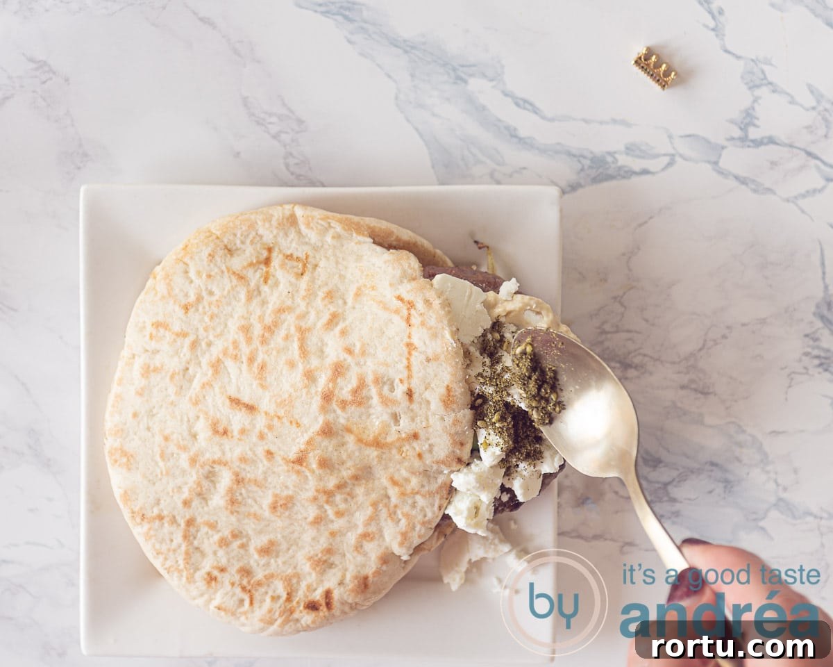 Greek-Style Burgers with Feta and Tzatziki Recipe 5 a spoon with za'atar spooned on top of crumbled feta