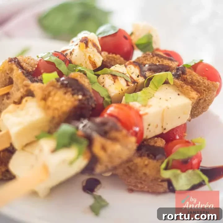 A square photo of a plate of skewers with halloumi, cherry tomatoes, garlic bread, basil and balsamic cream