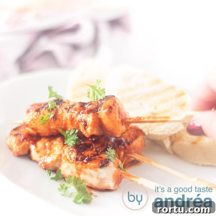 A square photo with a white plate with three chicken skewers, a hand grabbing one and three slices of toast