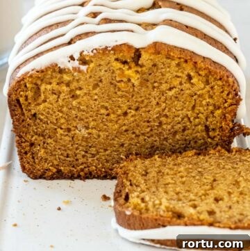 a loaf of easy pumpkin bread with glaze on top, with slice on the side
