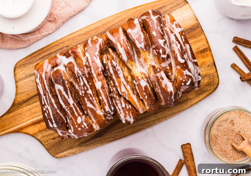 cinnamon pull apart bread with sweet powdered sugar glaze dripping, top shot