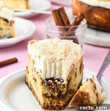 a slice of cinnamon roll cheesecake with cream cheese frosting