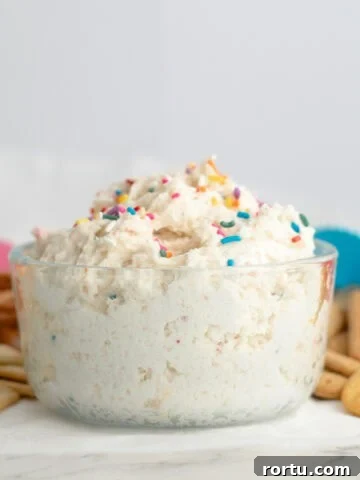 funfetti dip in a glass bowl with sprinkles surrounded by dipping options