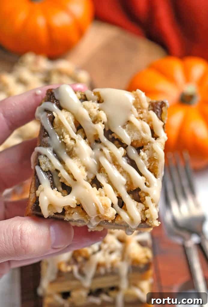 Paleo Vegan Pumpkin Crumble Bars for Fall Baking 5 hand holding a paleo vegan pumpkin pie crumb bar with the top showing the crumb and glaze