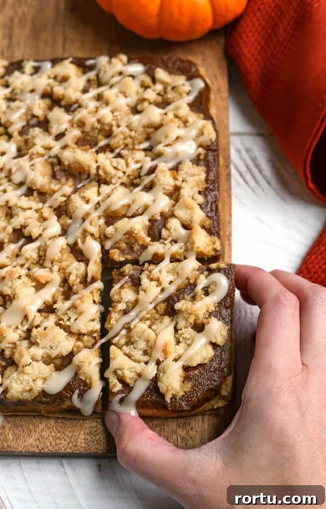 Paleo Vegan Pumpkin Crumble Bars for Fall Baking 7 hand reaching for a paleo pumpkin crumb bar