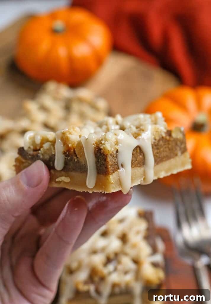 Paleo Vegan Pumpkin Crumble Bars for Fall Baking 8 a hand holding a paleo vegan pumpkin pie crumb bar