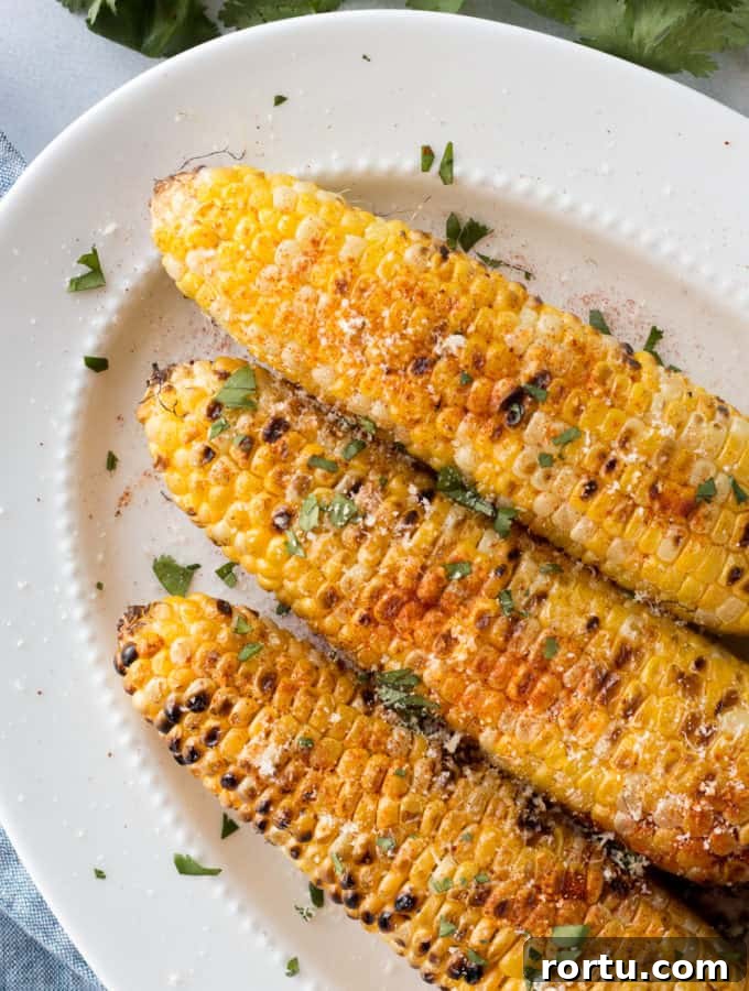top down shot of grilled corn on the cob with toppings on a white platter