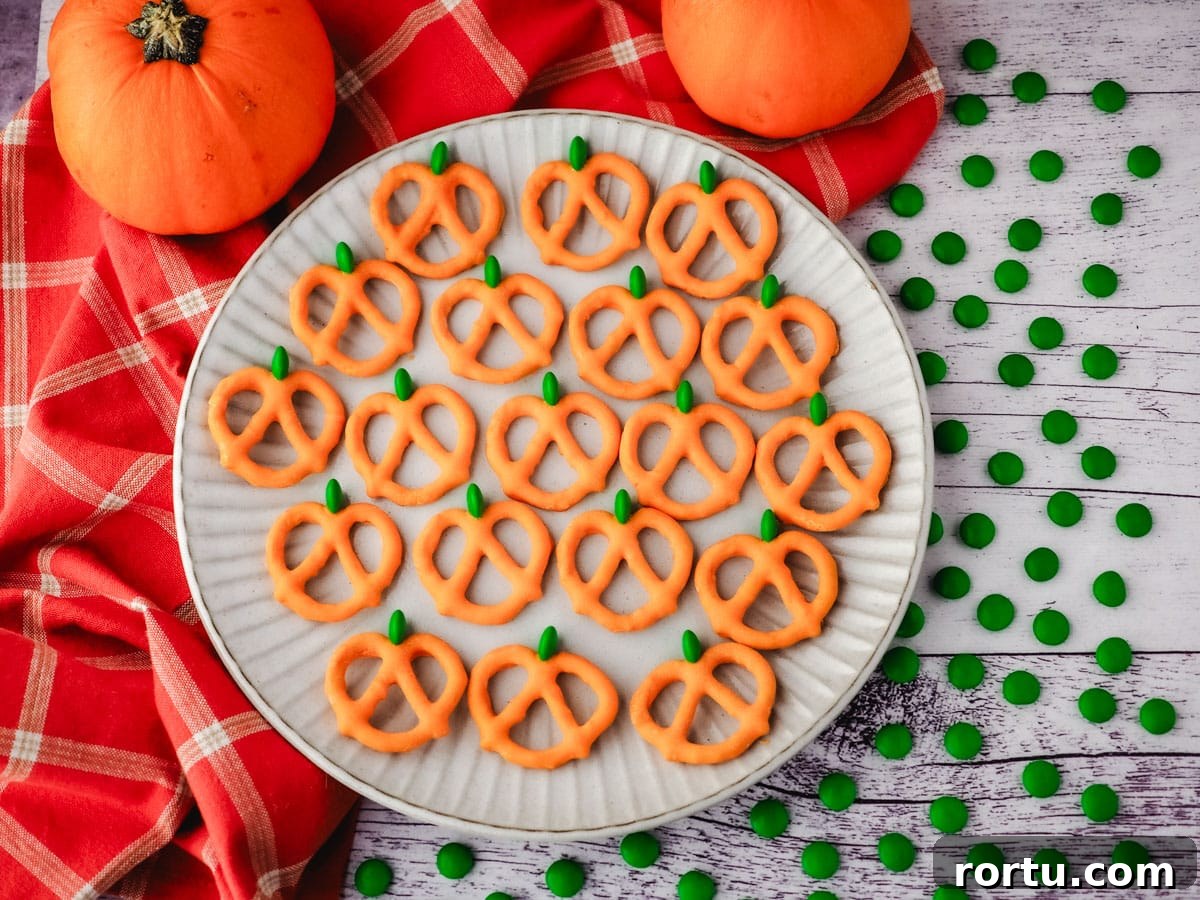 Pumpkin pretzels on a plate with a fall tea towel and mini pumpkins in the background.