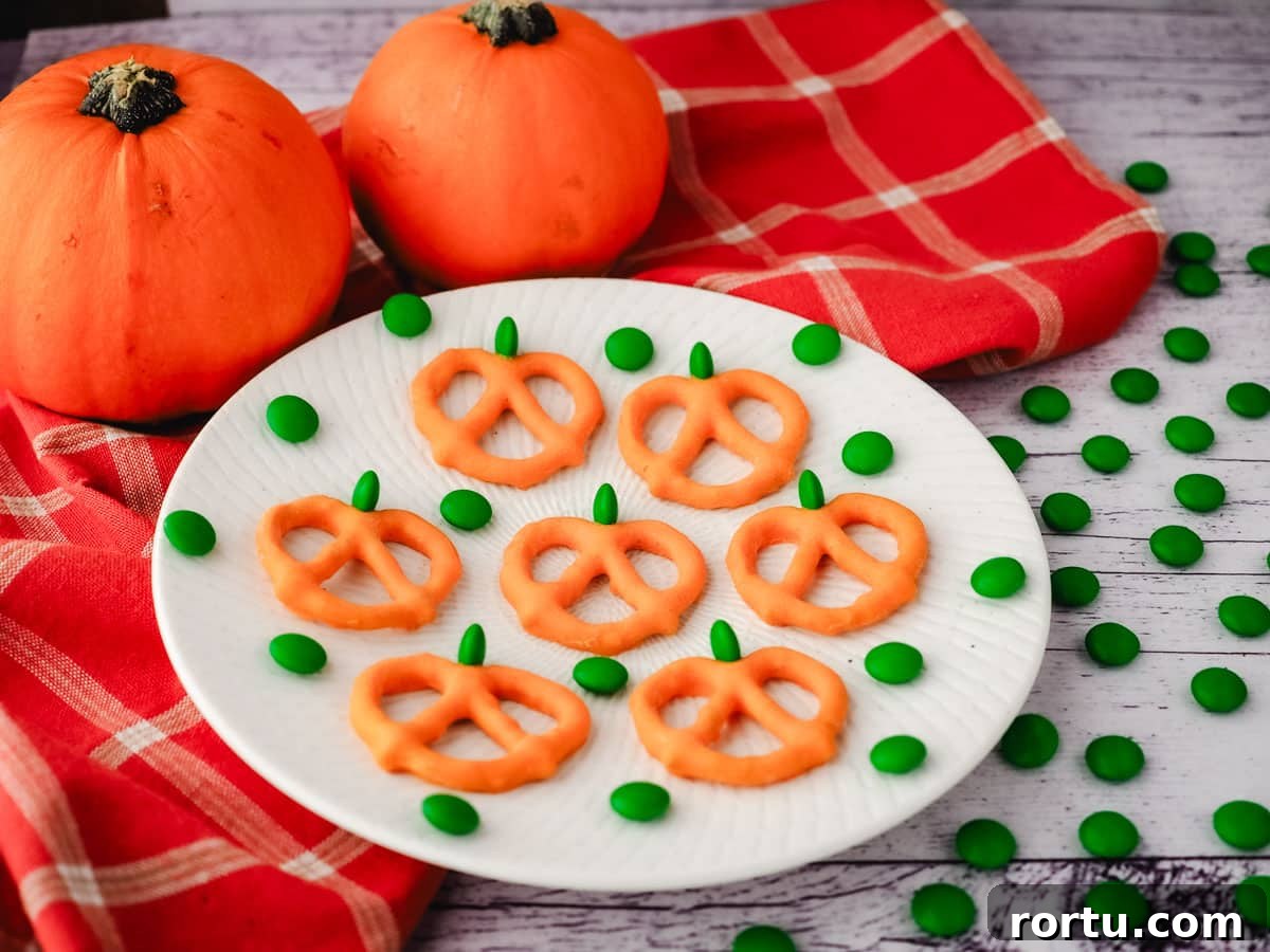 Pumpkin pretzels on a plate with a fall tea towel and mini pumpkins in the background.