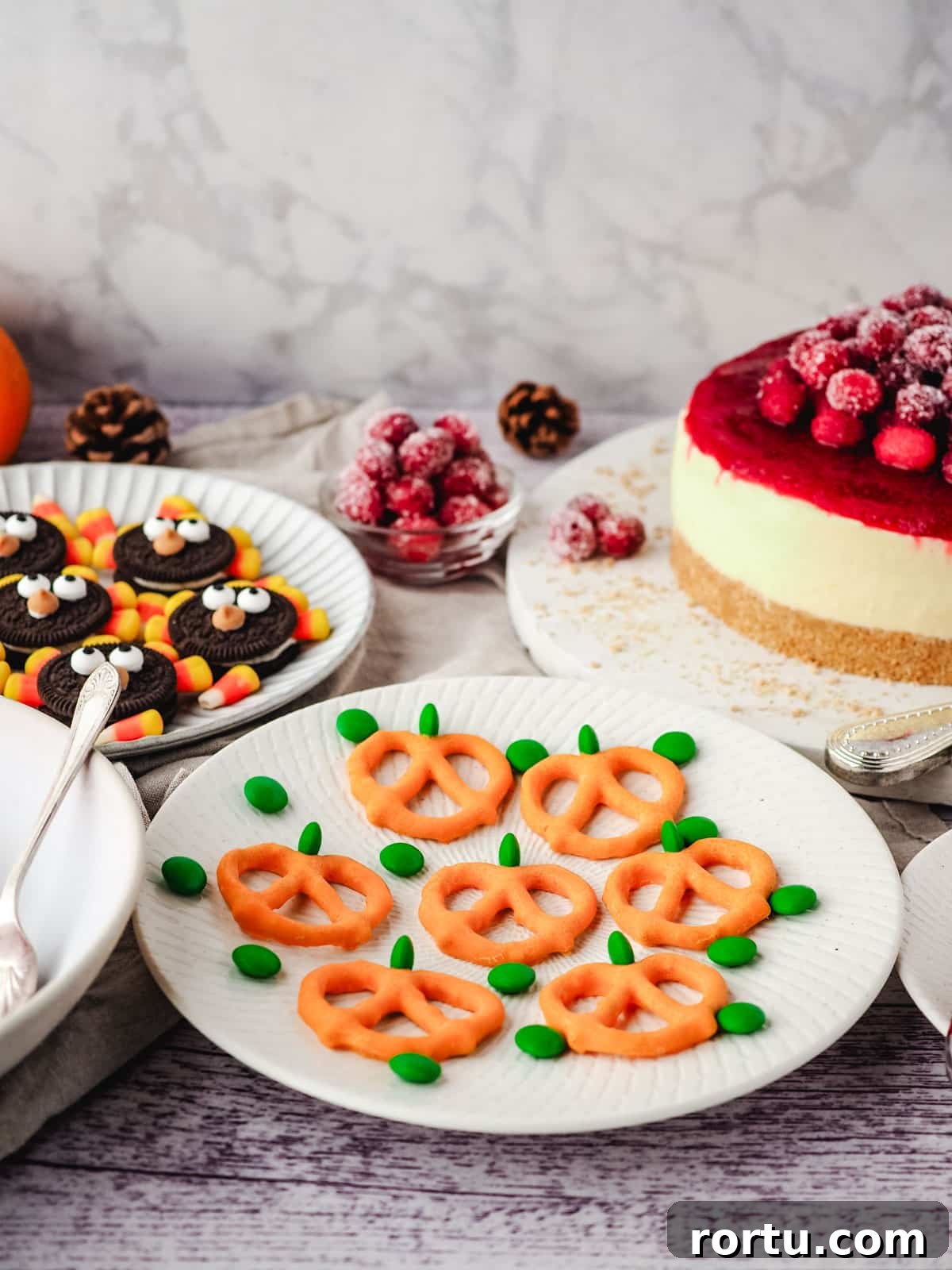 Pumpkin pretzels on a serving plate, on a Thanksgiving dessert table to cranberry cheesecake and turkey Oreos.