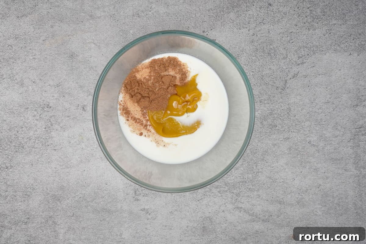 Milk, pumpkin puree, pumpkin pie spice, maple syrup and vanilla extract mixed in a bowl.