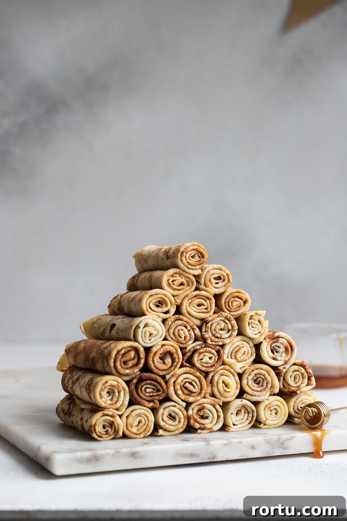 Polish Naleśniki (Crepes) Recipe: Classic Step-by-Step Guide 2 Rolled Polish crepes arranged in a pyramid on a marble board.