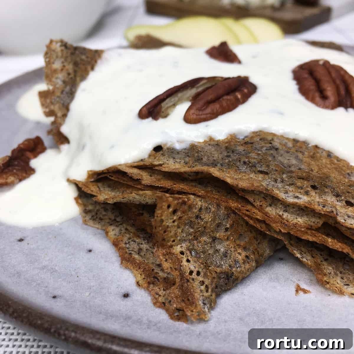 Folded French galettes with a savory filling, pecans, and slices of pear on a grey plate.