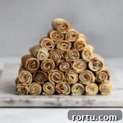 Rolled nalesniki arranged in a pyramid on a marble board.