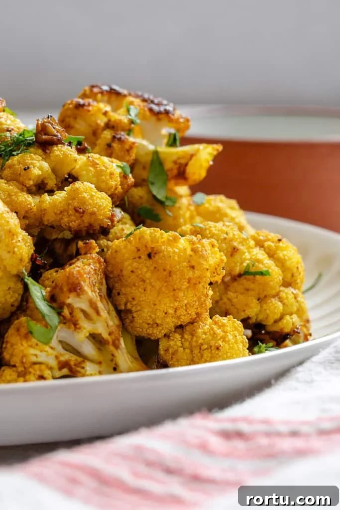 Curry-Roasted Cauliflower Recipe: Crispy Spiced Cauliflower Roast 7 Curry Roasted Cauliflower up close on white plate