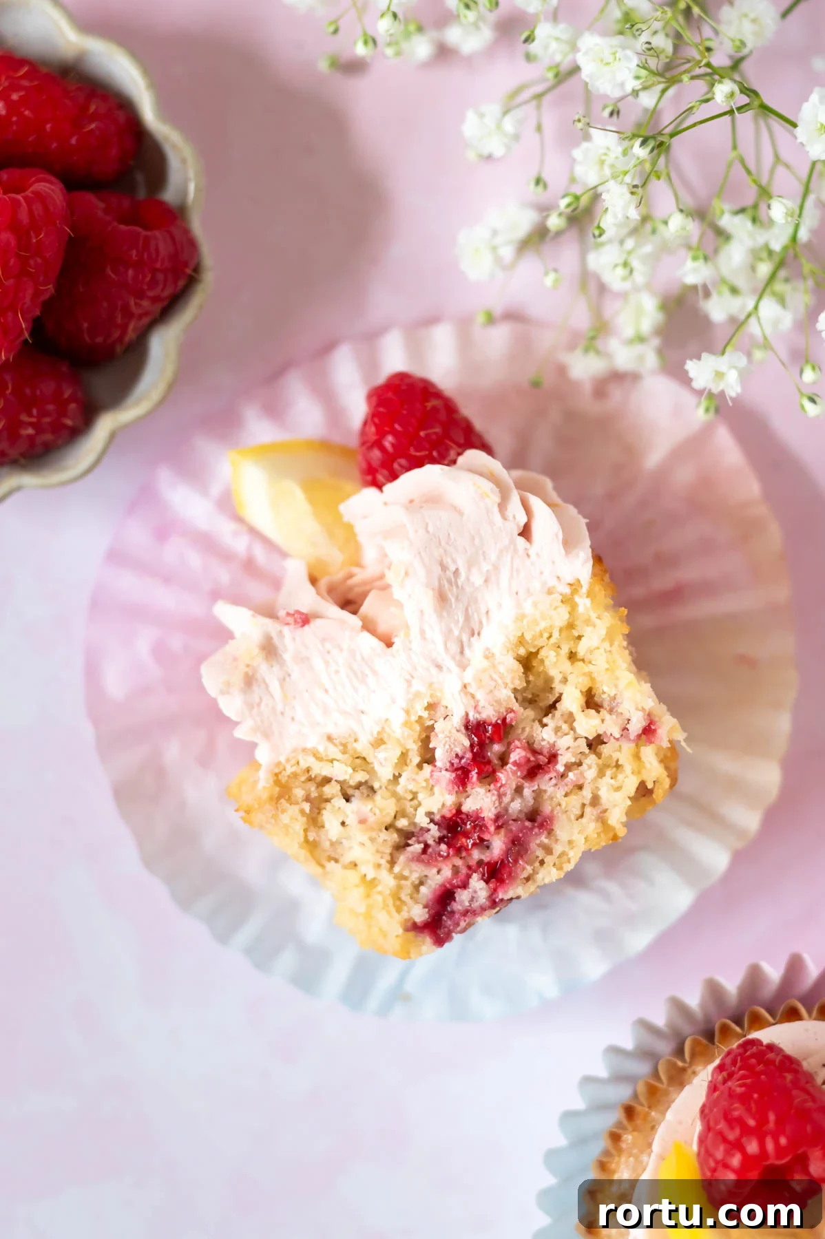 Lemon Raspberry Cupcakes Made from Scratch: Bright Summer Recipe 2 lemon raspberry cupcake cut in half in a cupcake liner showing raspberries through the cupcake