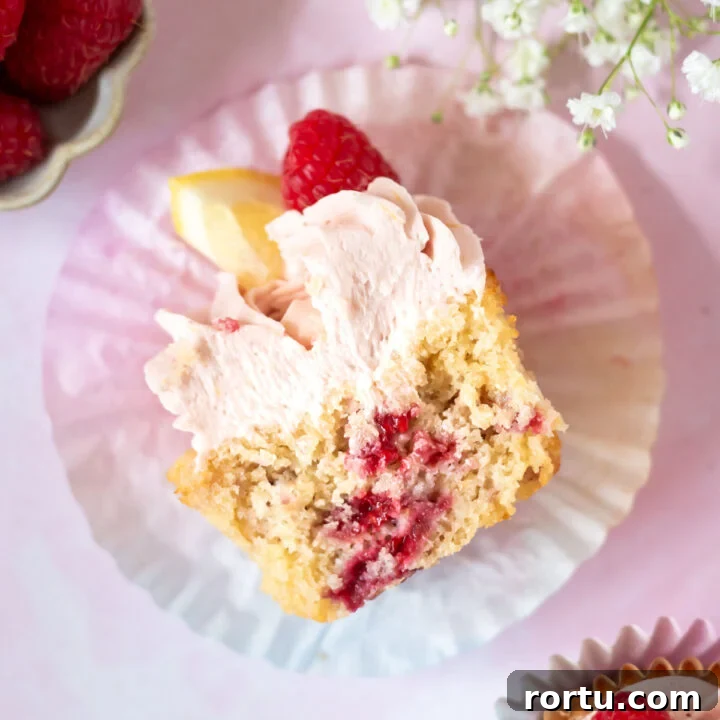 lemon raspberry cupcake cut in half in a cupcake liner showing raspberries through the cupcake
