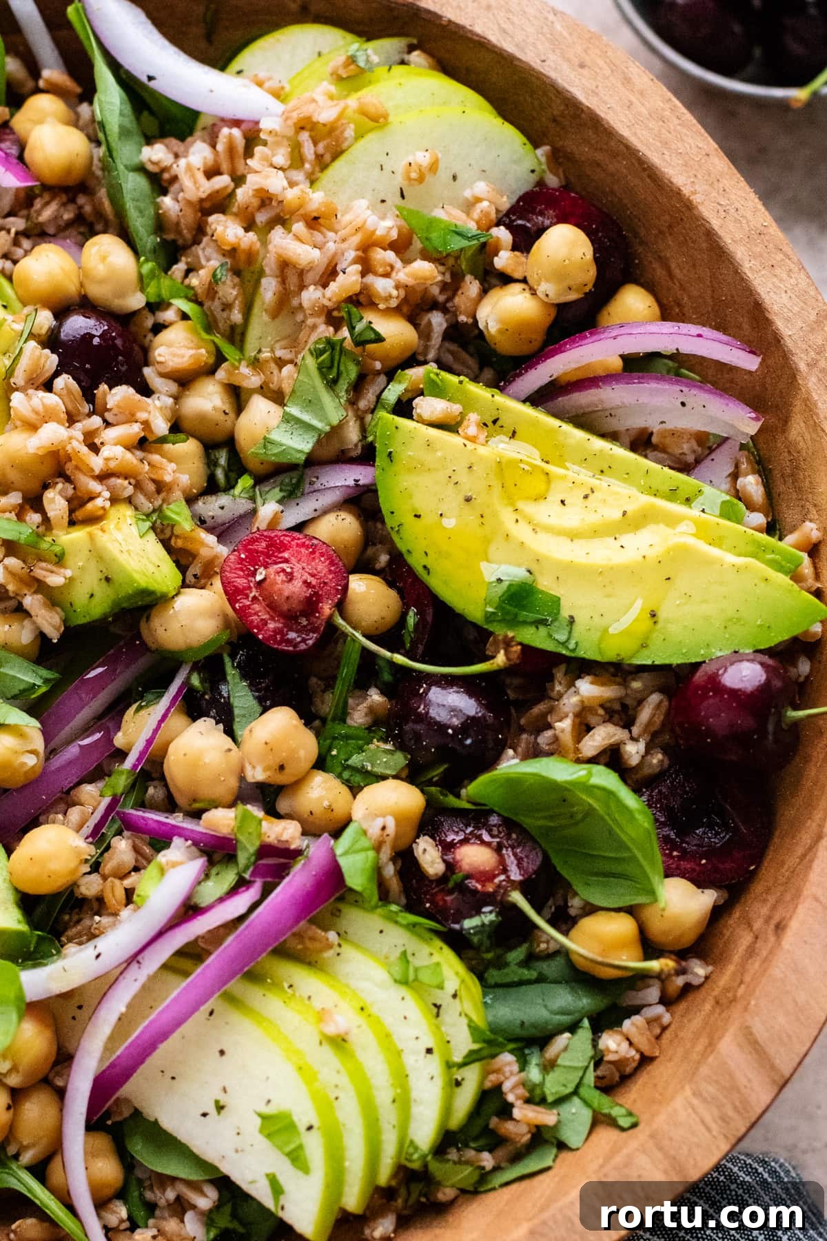 Summer Farro Salad with Cherries and Chickpeas for Picnic Menus 7 farro salad in a wooden bowl with avocado slices and cherries.