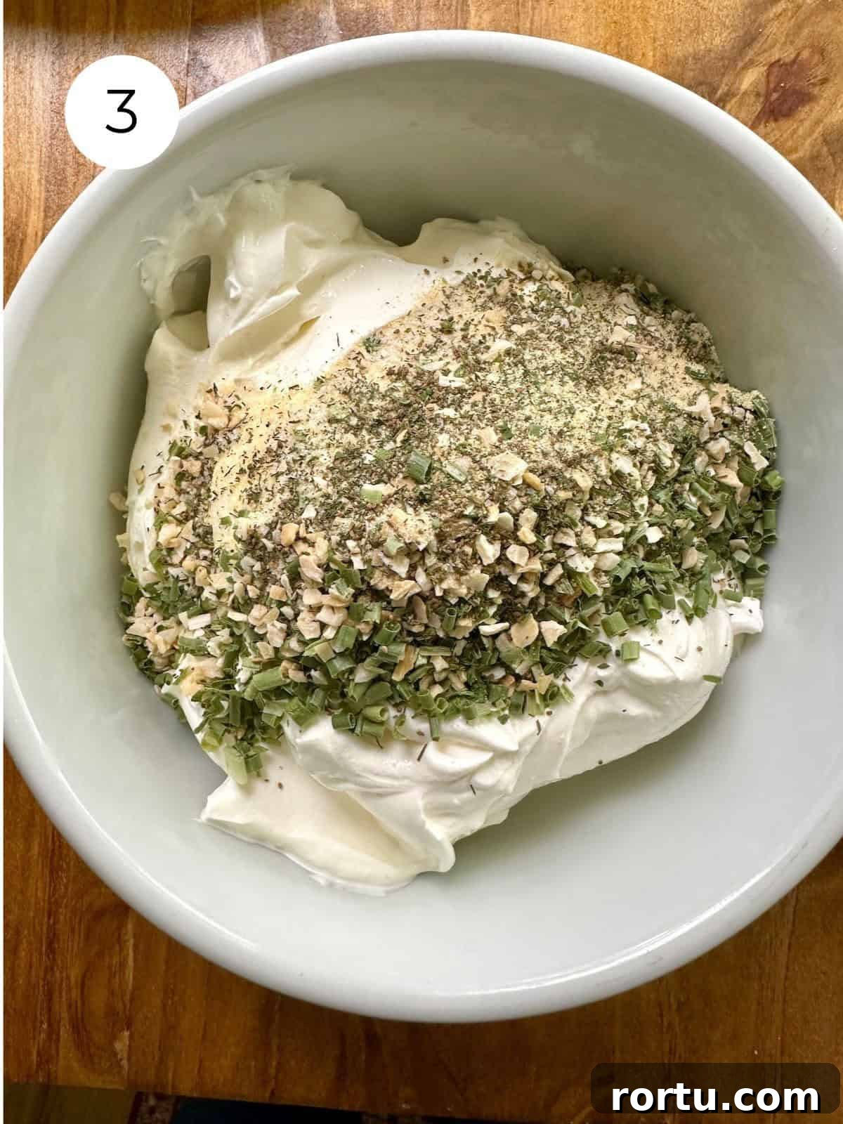 Dried herbs on top of a sour cream in a bowl.