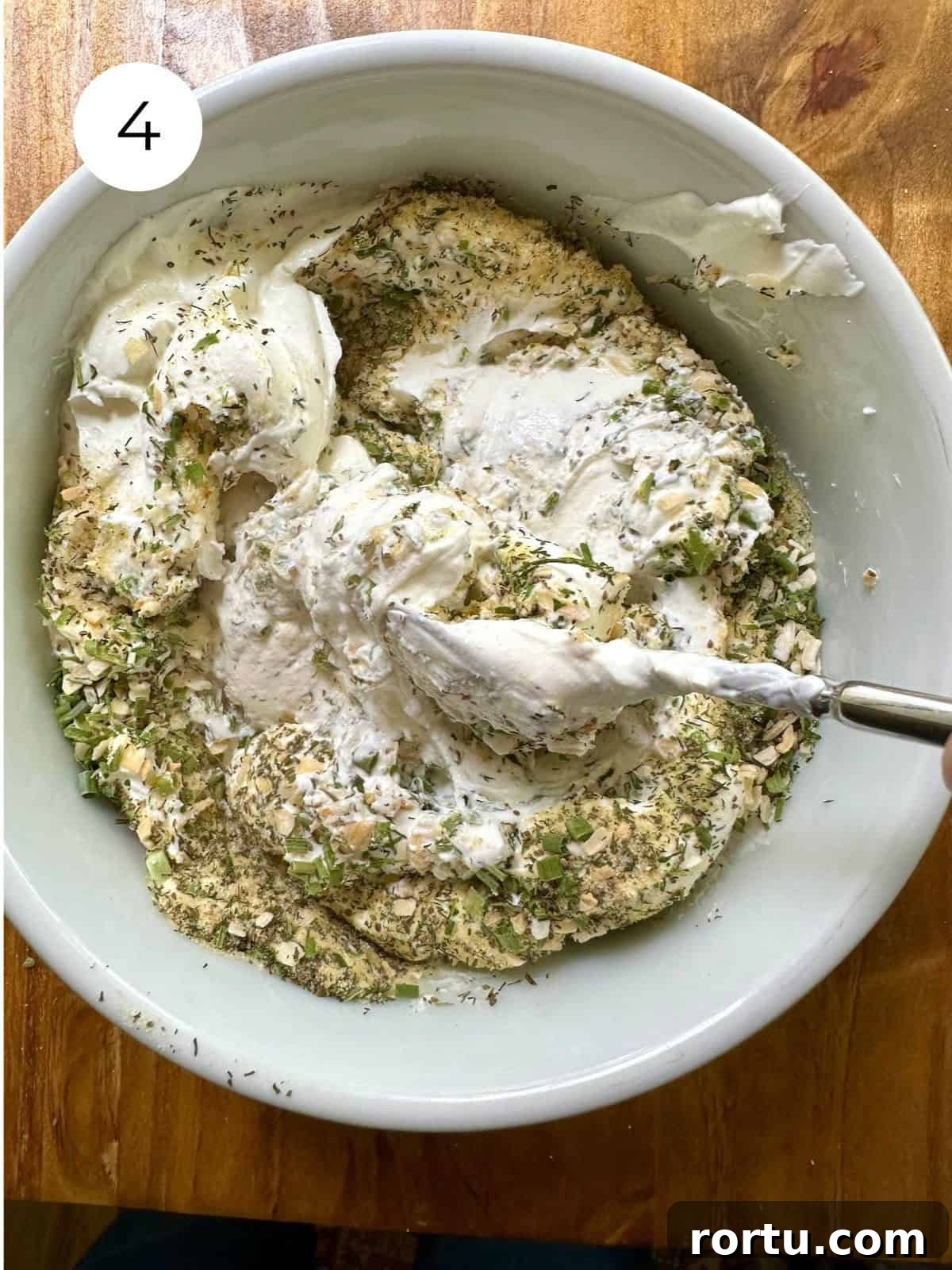 Dried herbs mixed with sour cream in a bowl.