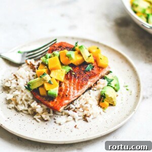 Pan-Seared Salmon on plate over rice and topped with mango and avocado salsa.