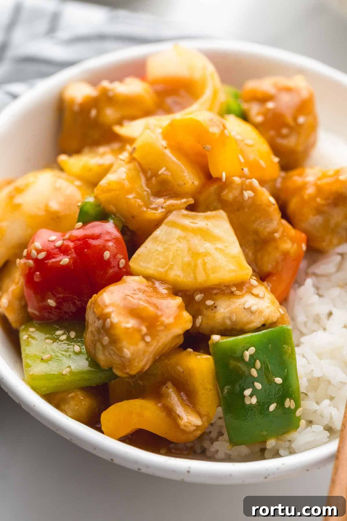 Sweet And Sour Chicken served over rice in a white bowl