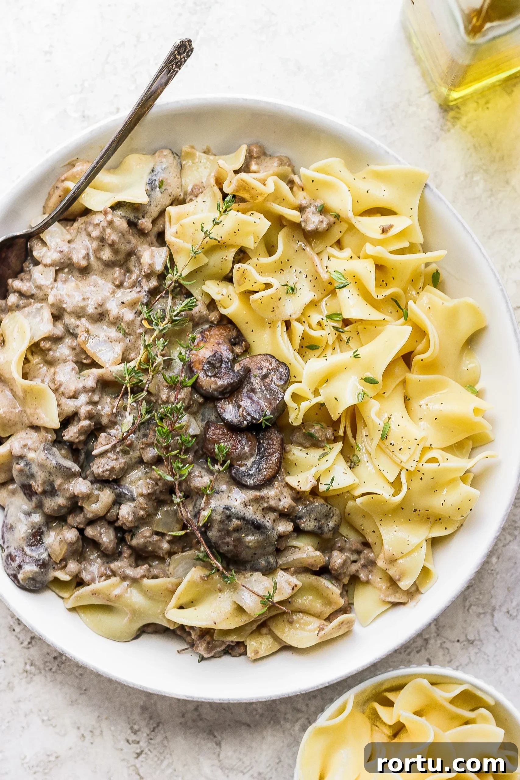Served beef stroganoff ground beef stroganoff in a bowl topped with fresh thyme