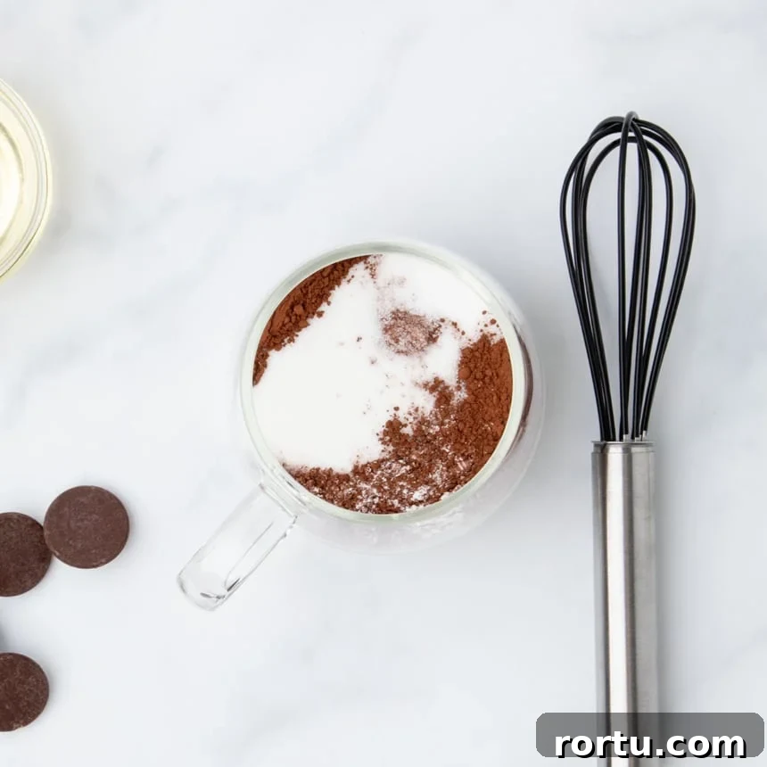 Dry ingredients added to a clear mug, including sugar and cocoa powder.