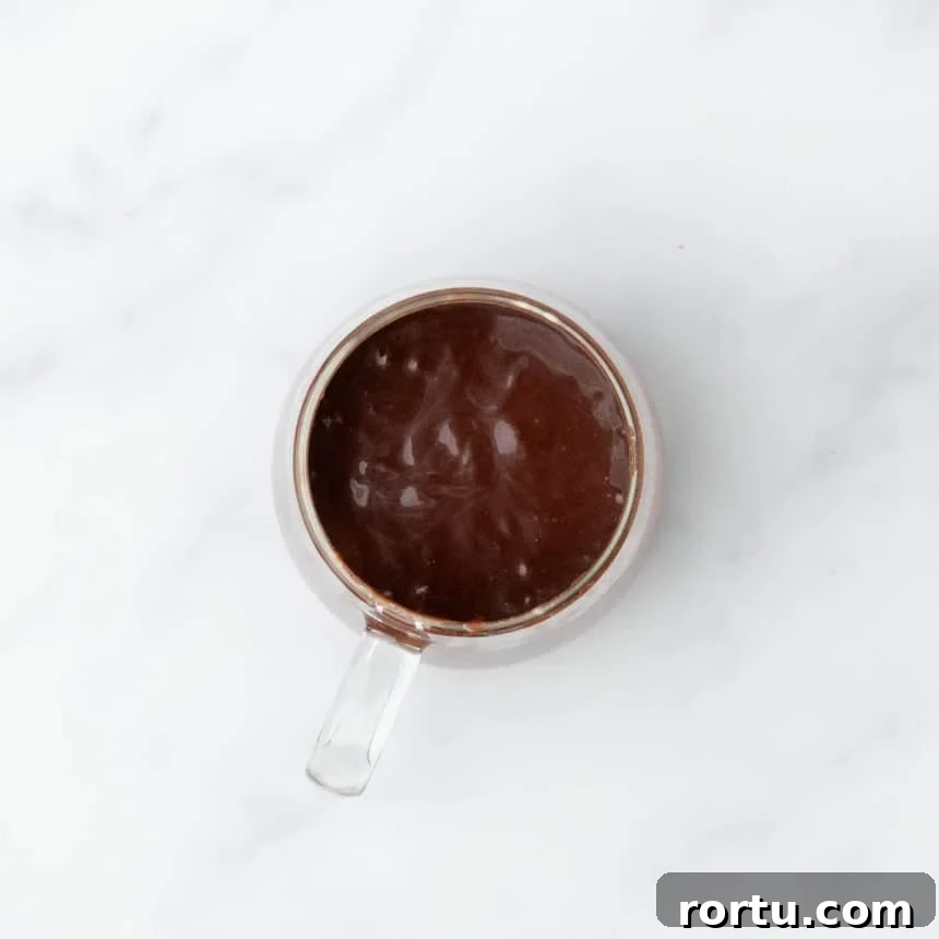 Glass mug filled with thick, glossy batter just before cooking.