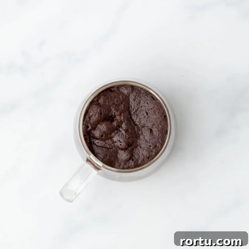 Baked gluten free mug cake with a rich texture, still in the glass mug.
