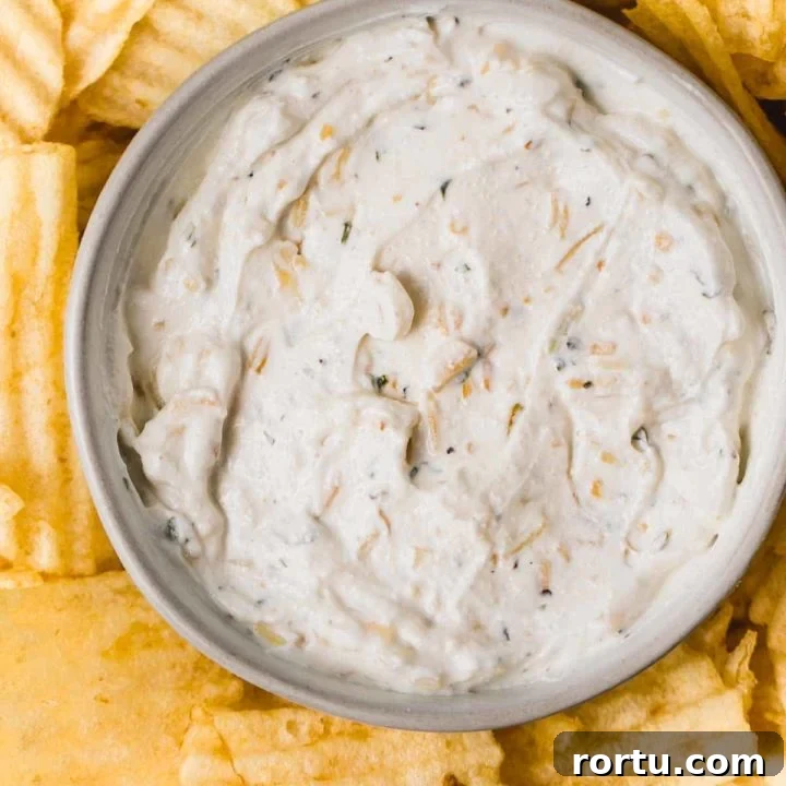 Gluten-free onion chip dip in a bowl next to wavy potato chips.