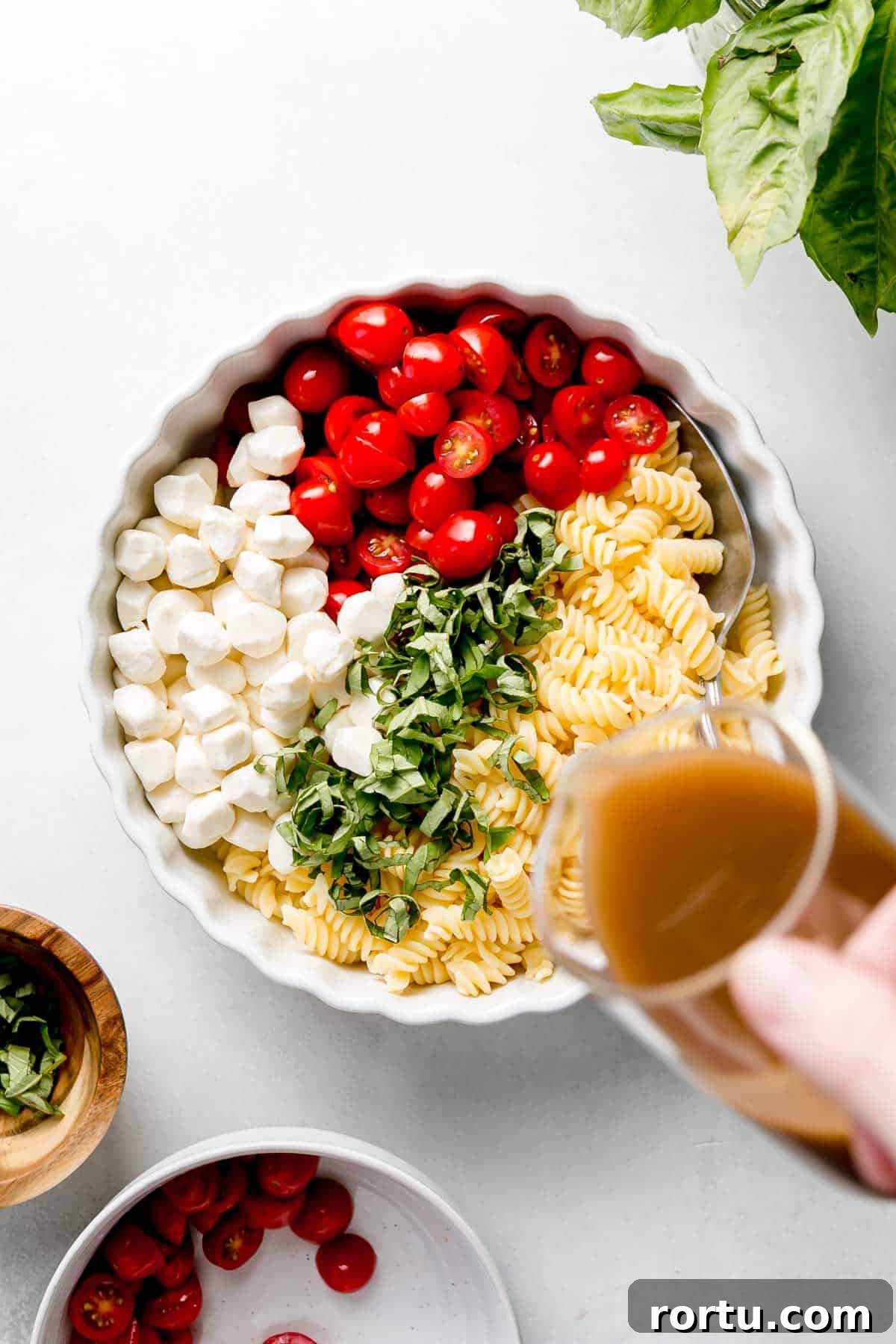 Pouring vinaigrette over dish with all of the salad ingredients.
