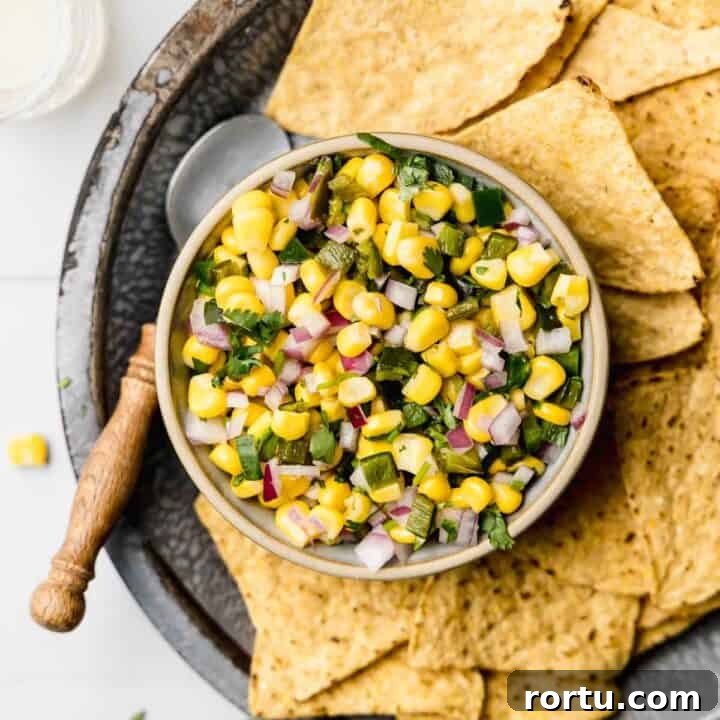 Chipotle roasted chili corn salsa in small bowl next to chips and spoon.