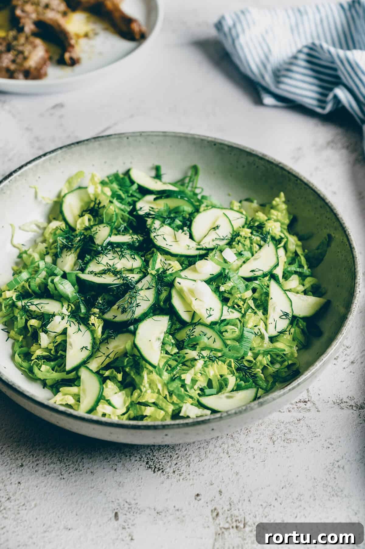 a large bowl of Greek lettuce salad on a rustic table.