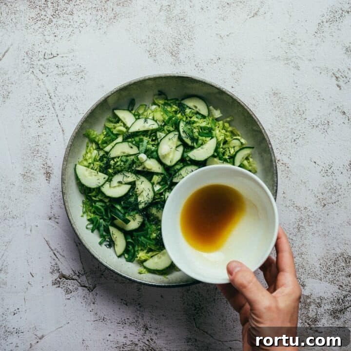 dressing being poured over a Greek lettuce salad.
