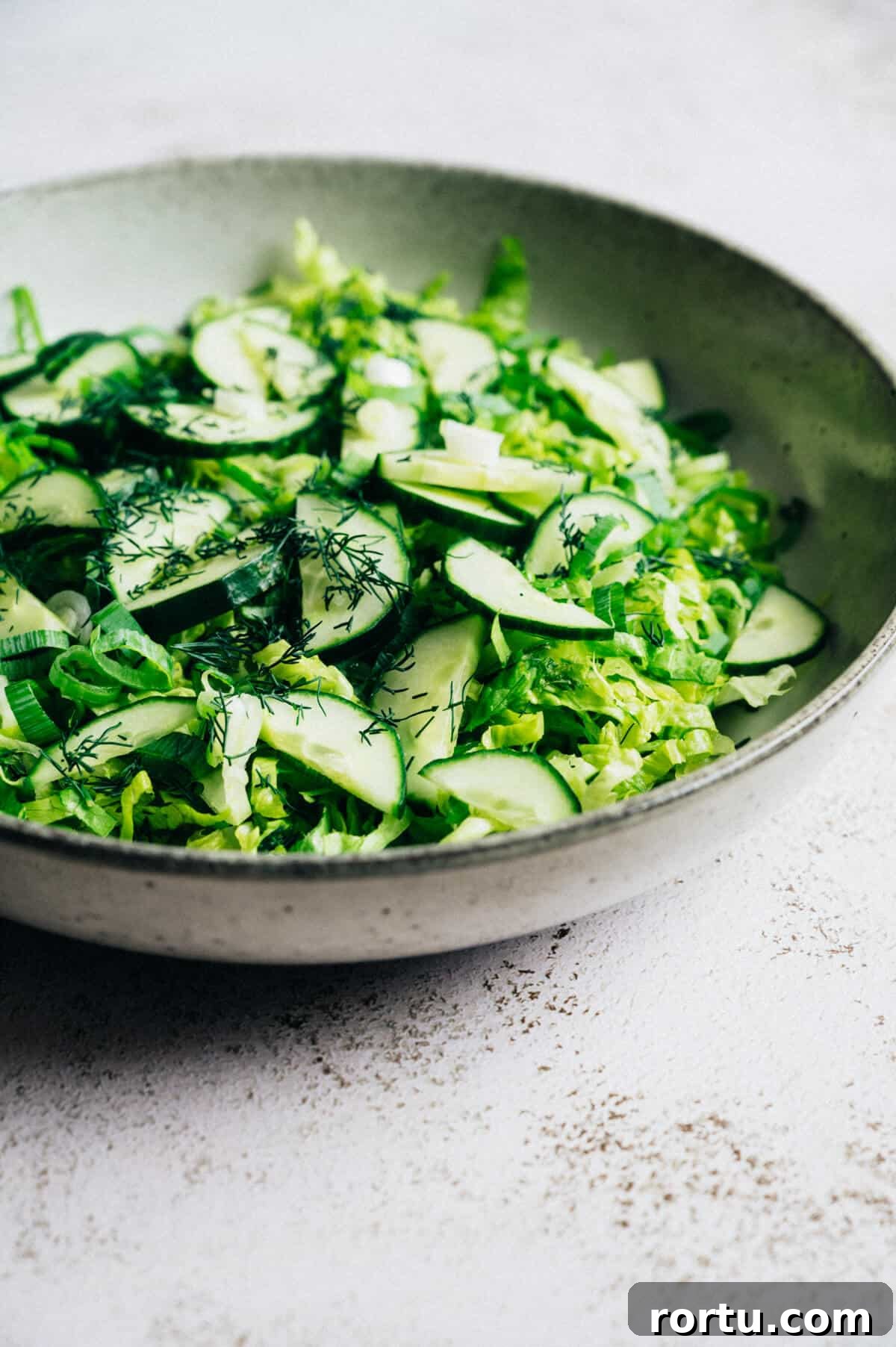 a large bowl of Greek lettuce salad on a rustic table.