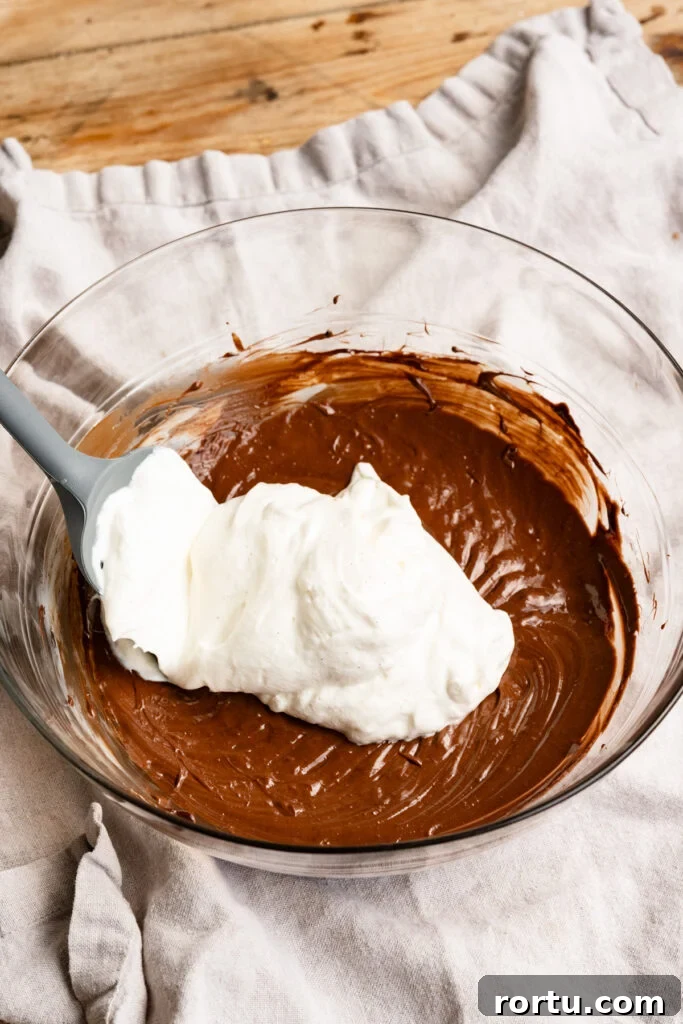 Whipped cream on top of chocolate butter mixture in a large mixing bowl.