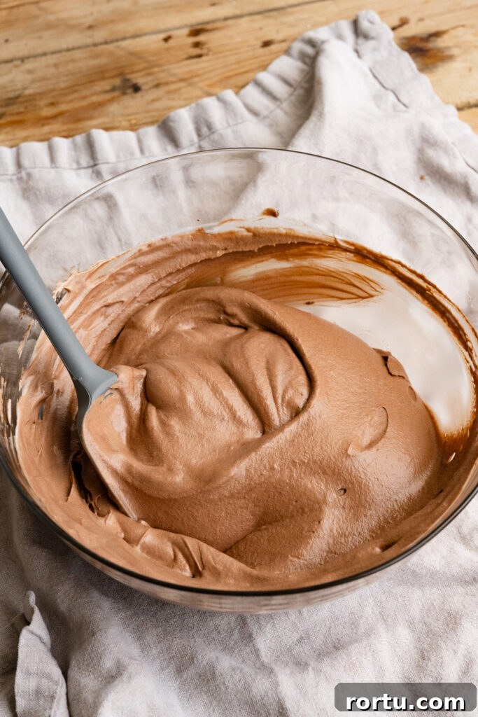 Chocolate mousse pie filling being stirred in a large mixing bowl with a spatula.