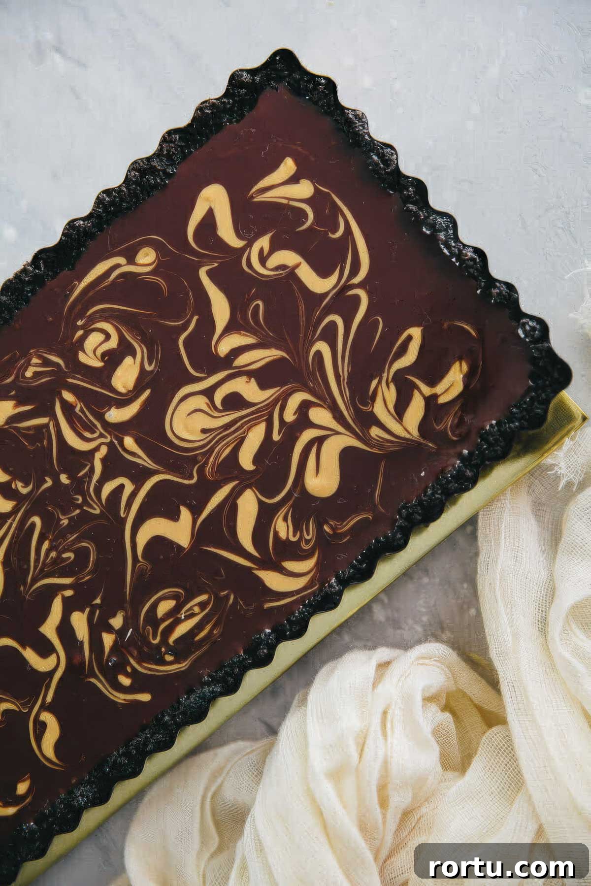 a chocolate ganache tart at an angle next to a cream-colored towel