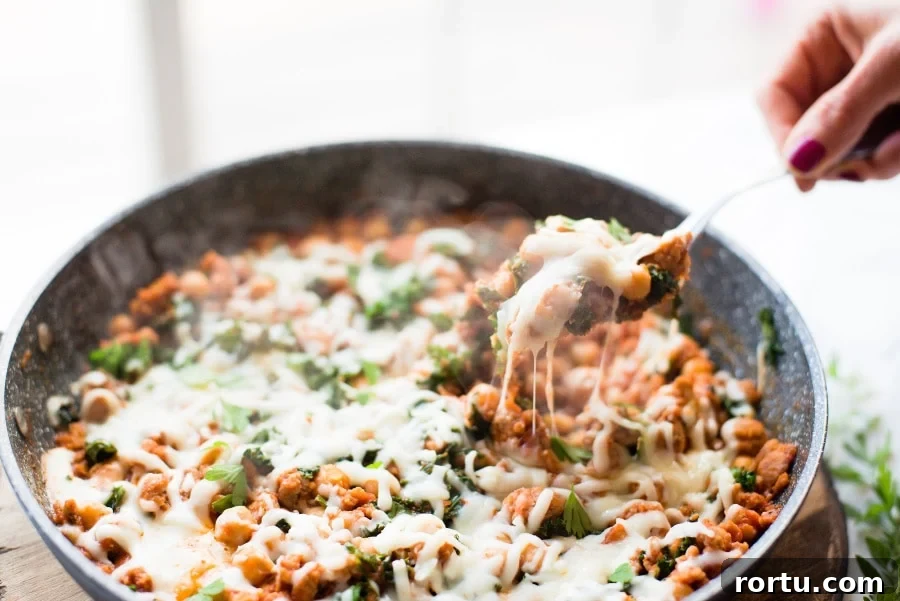 Sausage, White Bean & Kale Skillet Dinner Recipe 2 A warm from the stove photo of 21 Day Fix Sausage Bean and Kale Skillet topped with mozzarella cheese.