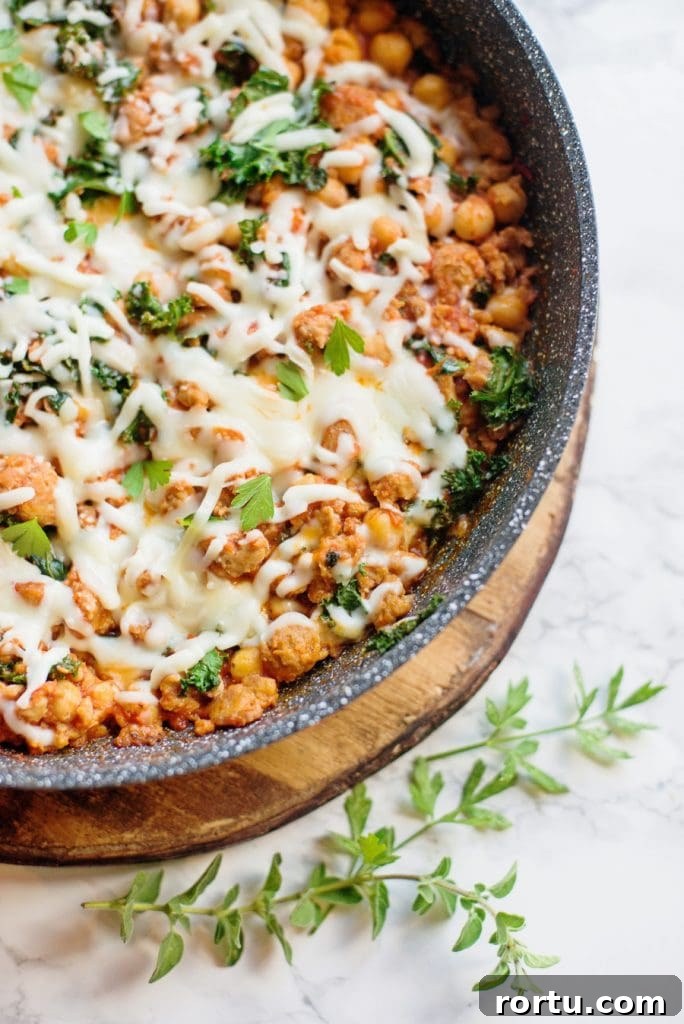 Sausage, White Bean & Kale Skillet Dinner Recipe 3 Healthy sausage bean and kale skillet topped with cheese sitting on a marble background.