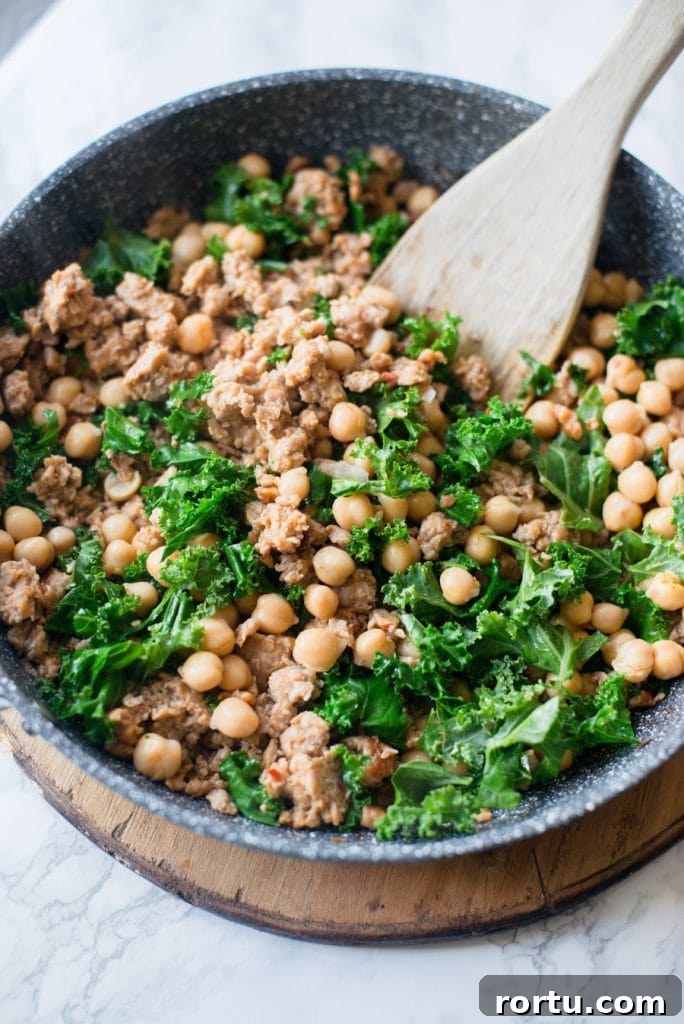 Sausage, White Bean & Kale Skillet Dinner Recipe 5 A Skillet is shown with italian chicken sausage, chick peas, and kale.
