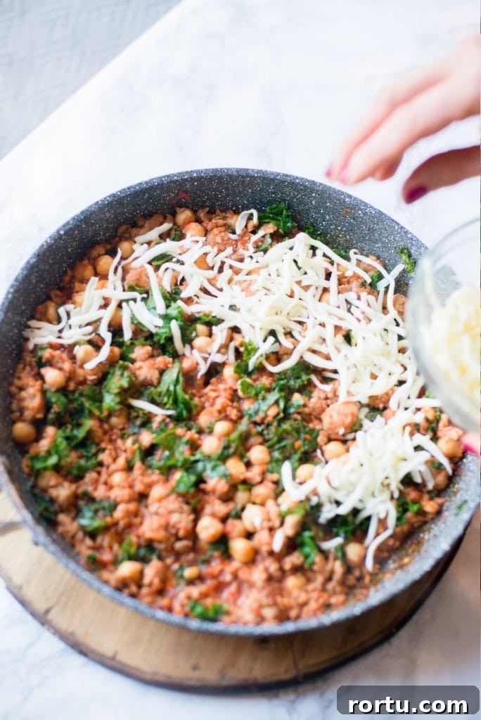 Sausage, White Bean & Kale Skillet Dinner Recipe 6 Cheese being placed on top of sausage bean and kale skillet